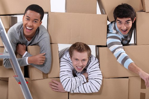Professional movers carrying boxes on a narrow West London staircase